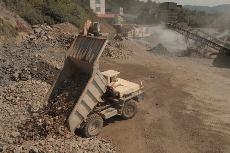 Truck unloads stones in a pile. Landscape of coal mining process. Heaps of stones and dust from sand.
